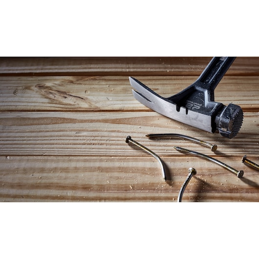 A DEWALT claw hammer is shown extracting bent nails from a wooden surface.