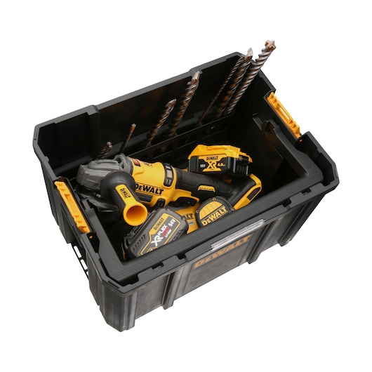 A DEWALT branded black tool storage box containing power tools, batteries, and several large drill bits. The items inside are yellow and black, matching the DEWALT color scheme.