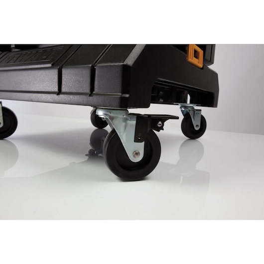 Close-up view of a black DEWALT wheeled tool storage box, highlighting its sturdy caster wheels and metal brackets on a reflective surface.
