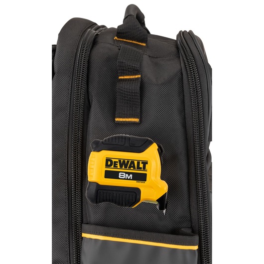 Close-up of a black and yellow DEWALT tape measure attached to a black tool bag with zippered compartments.