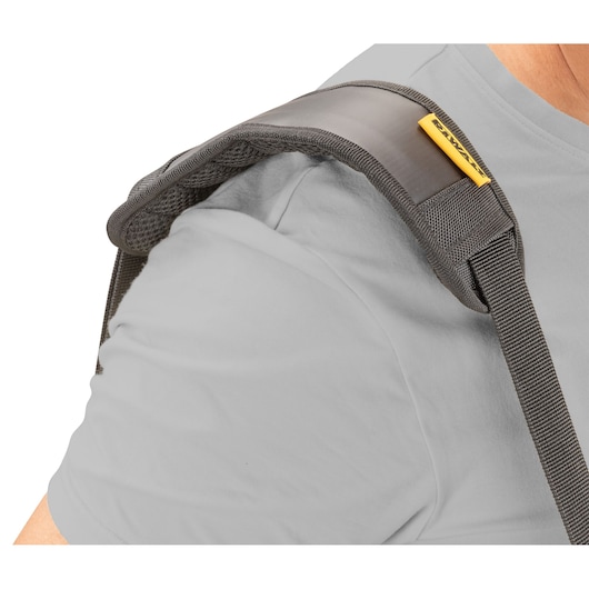 Close-up of a padded shoulder strap in grey with yellow DEWALT branding, worn over a light grey shirt.