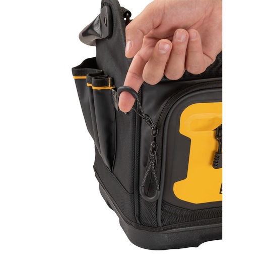 A close-up of a hand holding a zipper pull on a black and yellow DEWALT tool bag with external tool pockets.