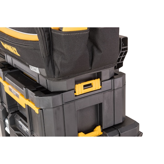Close-up image of stacked DEWALT TSTAK modular storage boxes with yellow latches, featuring a black and yellow tool bag on top.