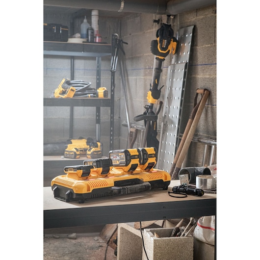 DEWALT photography products DCB548, DCB183, DCB104, DCB184 on workbench in workshop with tools and shelves.