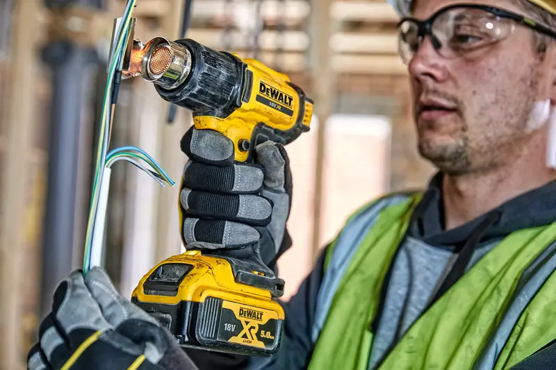 Photo of DEWALT DCE530N cordless heat gun used to work on wires at a construction site.
