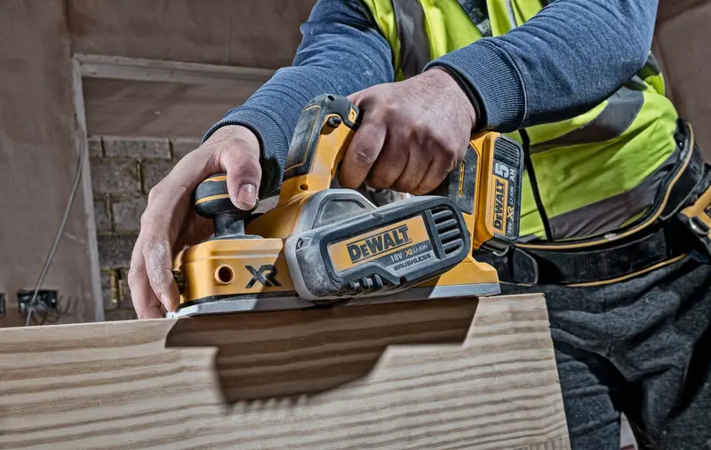 Photo of DEWALT DCP580N planer in use, yellow and black, on wooden board. Product category: Photography.