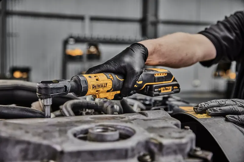 Photo of DEWALT ratchet tool DCF512N-XJ, DCF512N in use on engine, user wearing black gloves.