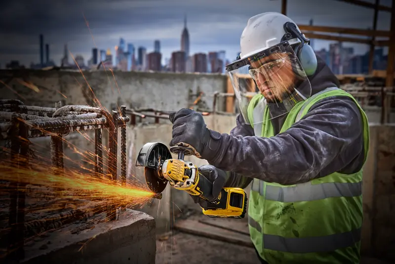Photo of worker using DEWALT grinder, SKUs DCG405P2-IN, DCG405P2, DCG405P2-GB, in construction site, sparks flying.